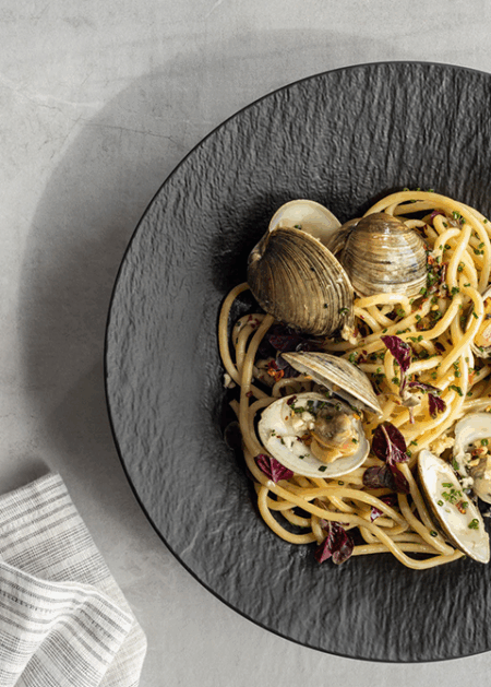 Gourmet pasta with clams on a black charger