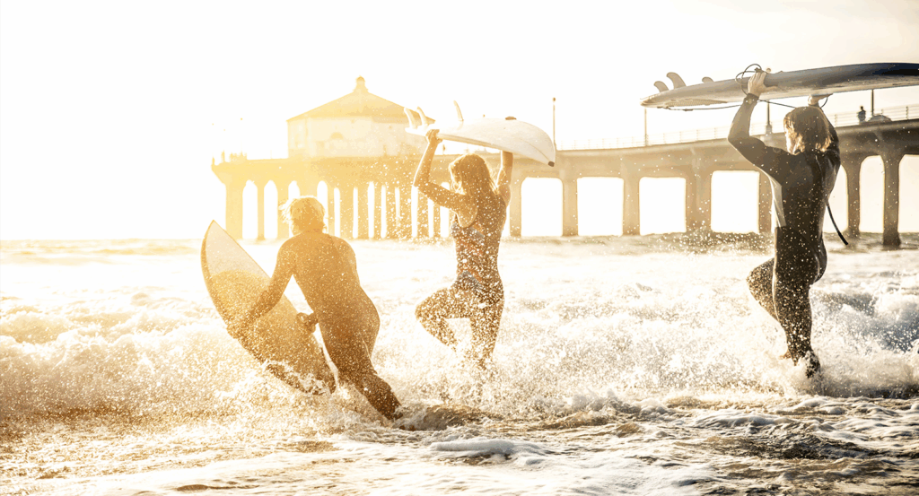 Three people enjoying Malibu surfing by the Pier.
