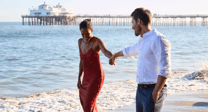 A woman in a red dress with her partner on Carbon Beach