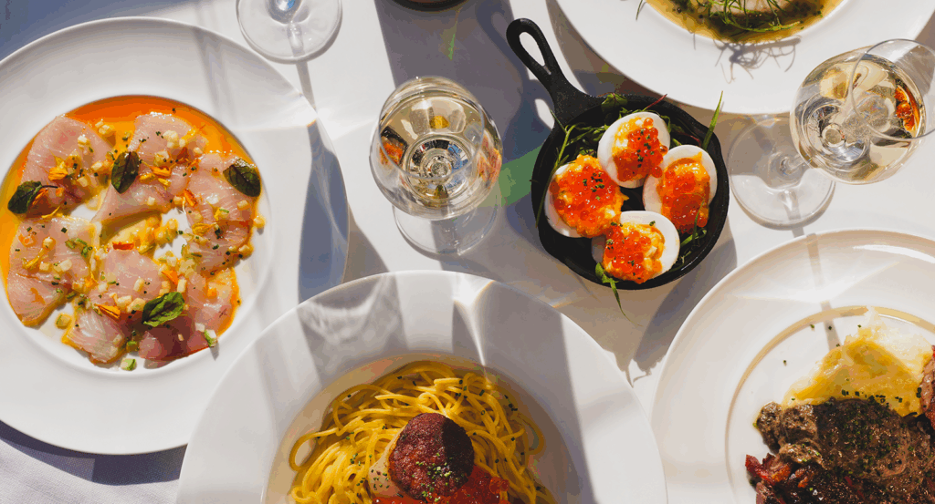 Overhead view of beautifully plated dishes and wine at Carbon Beach Club.