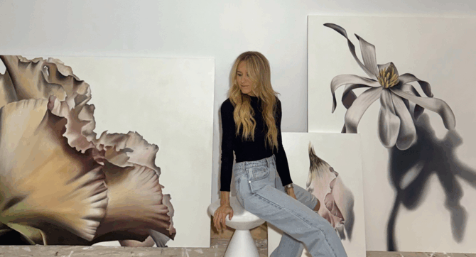 Renee Levin, artist in residence at Malibu Beach Inn, sitting amongst her paintings.